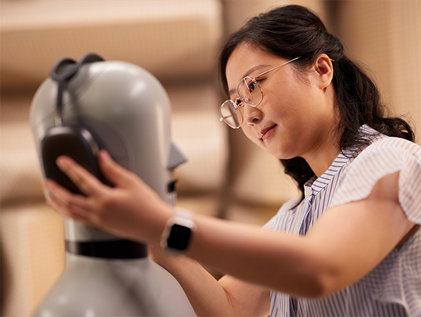 An Apple Hardware team member fitting Apple AirPods Max headphones on a mannequin in a lab.