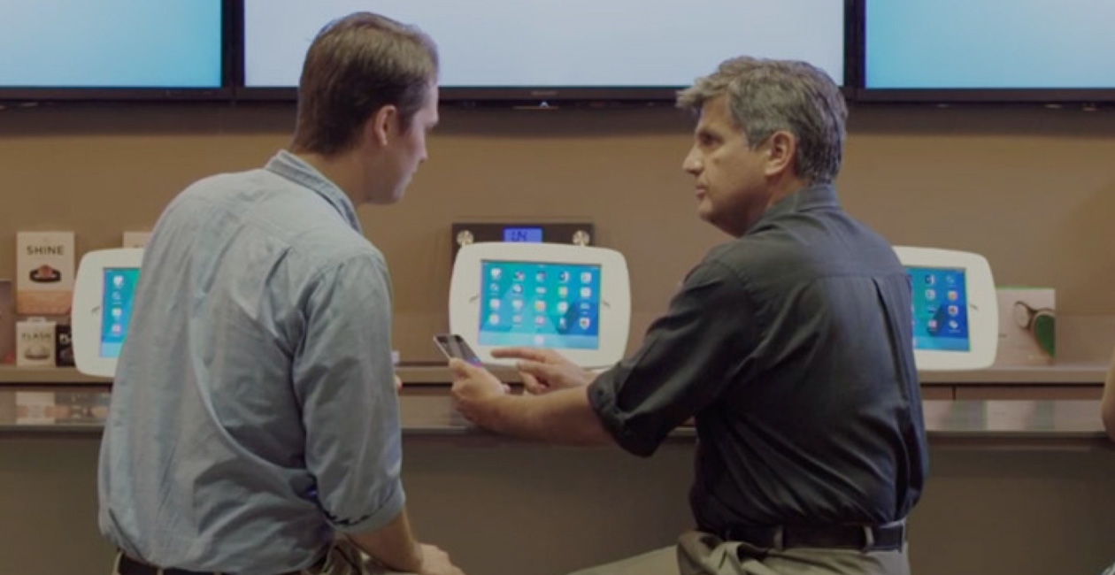 Deux hommes assis à l’O Bar, regardant l’écran d’un iPhone.