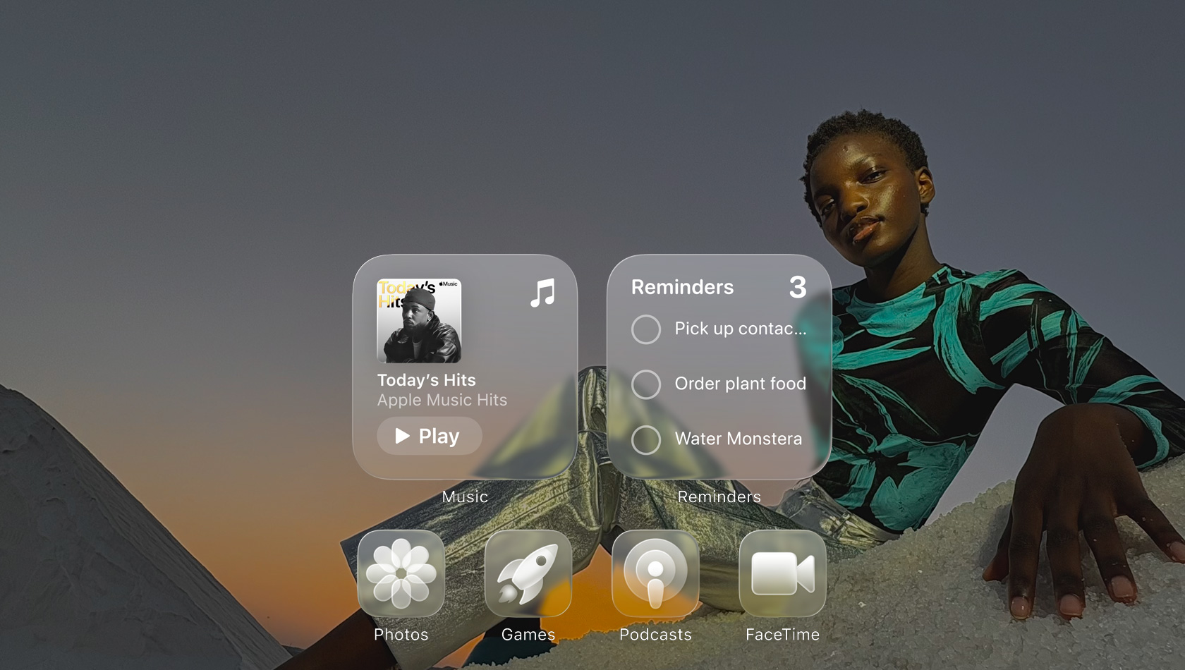 Écran en Liquid Glass avec des icônes d’app transparentes, comme Apple Music, Rappels, Photos, Jeux, Podcasts et FaceTime qui se réfractent contre le fond d’écran